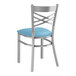 A Lancaster Table & Seating metal cross back chair with a blue vinyl cushion.