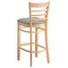 A Lancaster Table & Seating wooden bar stool with a light gray cushion.