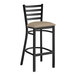 A Lancaster Table & Seating black ladder back bar stool with taupe vinyl padded seat.