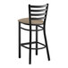 A Lancaster Table & Seating black ladder back bar stool with taupe vinyl cushion.