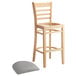 A Lancaster Table & Seating wooden bar stool with a light gray vinyl seat.