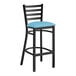 A Lancaster Table & Seating black ladder back bar stool with a blue vinyl cushion.