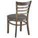 A Lancaster Table & Seating wooden ladder back chair with a dark gray cushion.