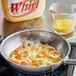 A frying pan with onions and peppers cooking in Whirl Butter Flavored Oil.