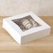 A 9" x 9" white bakery box with a transparent window filled with pastries.