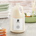 A jug of ProTerra Honey and Vanilla conditioner sitting on a counter next to towels.