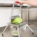 A person using a Vollrath Redco Lettuce King vegetable cutter to slice lettuce on a counter.