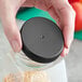 A hand holding a jar with a 63/400 black ribbed plastic cap on it.