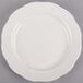 A CAC ivory china plate with a scalloped edge on a gray surface.