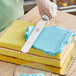 A person using a Choice straight blade spatula to frost a cake.