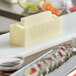 A white rectangular Emperor's Select sushi mold on a white surface next to sushi.