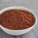 A bowl of Cacao Barry cocoa powder on a gray surface.