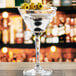 A close up of a martini glass with olives on top.