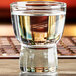 An Anchor Hocking sake shot glass filled with clear liquid on a table.