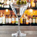 A close-up of a martini glass with olives on a table.