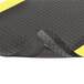 A black and yellow rubber mat with a yellow stripe in a black and yellow diamond plate pattern.