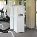 A Mayne Lakeland white towel valet on a gym floor with exercise equipment.
