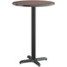 A Lancaster Table & Seating round bar table with a reversible walnut and oak laminated top on a black base.