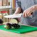 A person using a Choice Classic Chef Knife to cut eggplant on a cutting board.