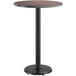 A round Lancaster Table & Seating bar height table with a reversible walnut and oak laminated top on a black base.