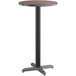 A round bar height table with a black base and a reversible walnut and oak top.