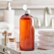 A Boston Round 32 oz. amber plastic bottle with white flip top lid on a tray with towels.