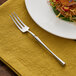 An Acopa Hepburn stainless steel cocktail fork on a plate of food.