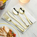 A Visions Classic heavy weight gold plastic cutlery set with a fork and knife on a white napkin.