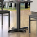 A Lancaster Table & Seating black stamped steel table base with leveling feet.