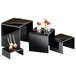 A black Cal-Mil nesting riser set on a black and white table with desserts.