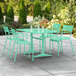 A Lancaster Table & Seating seafoam powder-coated aluminum table with 4 arm chairs on a patio.