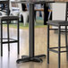 A Lancaster Table & Seating black bar height column table base with leveling feet under a table in a restaurant.