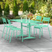 A seafoam green table with an umbrella hole and four chairs on a patio.