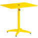 A yellow Lancaster Table & Seating outdoor table with a metal stand and umbrella hole.