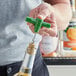 A hand using a green plastic pocket corkscrew to open a bottle of wine.