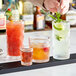 A bartender pours drinks into Acopa Zion old fashioned glasses on a bar.