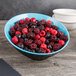 A blue and black slanted melamine bowl of berries on a table.