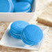 Blue macaroons on a plate with blue icing.