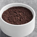 A bowl of Ghirardelli Midnight Dutch Cocoa Powder on a gray surface.