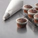 Un-iced Rich's Allen chocolate cupcakes on a cooling rack with a white wrapper on one cupcake.