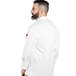 A man wearing a white Uncommon Chef long sleeve chef coat with a white mesh back and white sleeves.