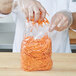 A person in gloves putting carrots in a LK Packaging plastic food bag.