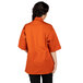 A woman wearing an orange Uncommon Chef Venture Pro Vent short sleeve chef coat.