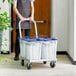 A man using an aluminum ice tote dolly to transport three buckets.