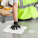 A person wearing a safety vest and gloves cleaning a counter with a Lavex white industrial wiper.