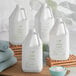A group of white Nourish body lotion jugs with green labels next to a bowl of towels.