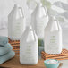 A group of white Nourish conditioner jugs with green labels next to a bowl of towels.