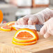 A hand using a Schraf serrated paring knife to slice an orange.