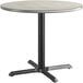 A round table with a black base and a reversible grey and white laminated top.