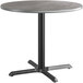 A round table with a metal base and a grey and white reversible top.